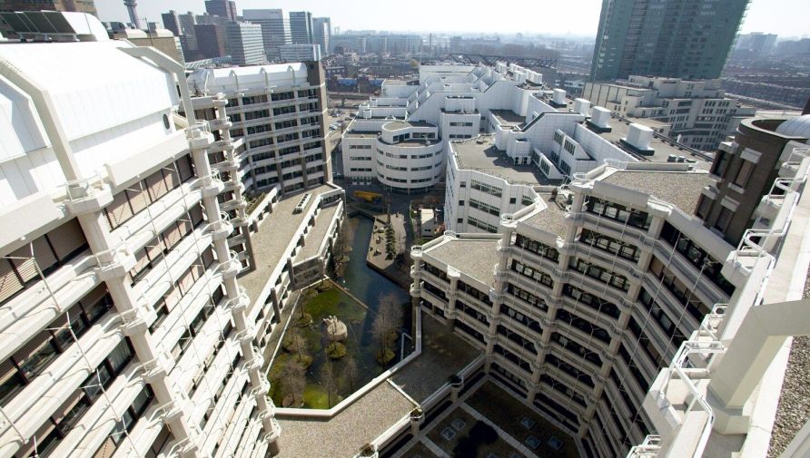 Het voormalige pand van het Ministerie van Buitenlandse Zaken. Het witte, hoge gebouw is vlakbij station Den Haag. Tussen de gebouwen is een water.Centraal. 