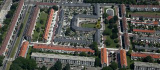 Foto van Moerwijk vanuit de lucht. op de afbeelding zijn appartementencomplexen te zien, maar ook een park, singel en veel groen.