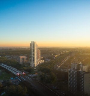 Foto van nieuwbouwproject Levels vanaf de hoogte met een ondergaande zon op de achtergrond. Het flatgebouw is het hoogste gebouw op de foto.