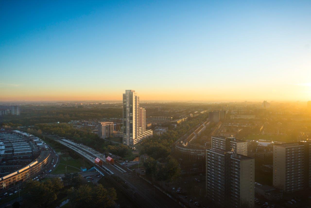 Foto van nieuwbouwproject Levels vanaf de hoogte met een ondergaande zon op de achtergrond. Het flatgebouw is het hoogste gebouw op de foto.