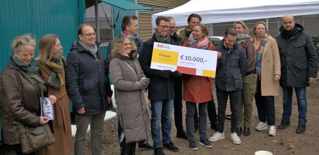 Anne Koning overhandigt cheque aan wethouder Volkshuisvestiging Martijn Balster en projectleider Timo Wagteveld