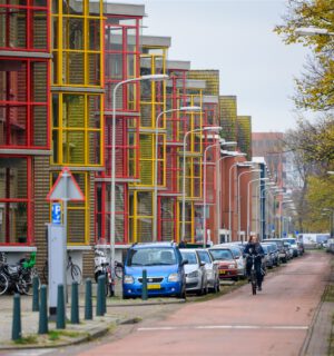 Straat in Molenwijk met flats, geparkeerde auto's en fietser.