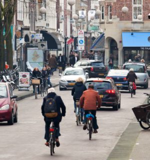 Drukke straat in de binnenstad van Den Haag met auto's, fietsers en voetgangers.
